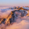 Un coucher de soleil flamboyant sur le massif de Belledonne, baigné par une mer de nuages dorés. Une photographie de Gaëtan Michel, capturant l'atmosphère magique des Alpes à la tombée du jour. Coucher de soleil sur Belledonne avec mer de nuages, lumière dorée - Photo de paysage par Gaëtan Michel