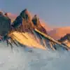 Les Aiguilles d’Arves baignées par les dernières lueurs d’un coucher de soleil hivernal, offrant un spectacle de lumière dorée sur les sommets enneigés. Une photographie de Gaëtan Michel, capturant la magie des Alpes en hiver. Aiguilles d’Arves enneigées au coucher de soleil, lumière dorée sur les sommets alpins, photo de montagne par Gaëtan Michel