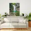 Tirage photo encadré d’une cascade dans le torrent de l’Alloix en Chartreuse, accroché au mur d’un salon moderne. L’image montre une cascade avec une eau turquoise s’écoulant entre des rochers moussus, entourée d’une forêt alpine. Le cadre est suspendu au-dessus d’un canapé blanc, entre deux plantes vertes en pot. Photo prise par Gaëtan Michel