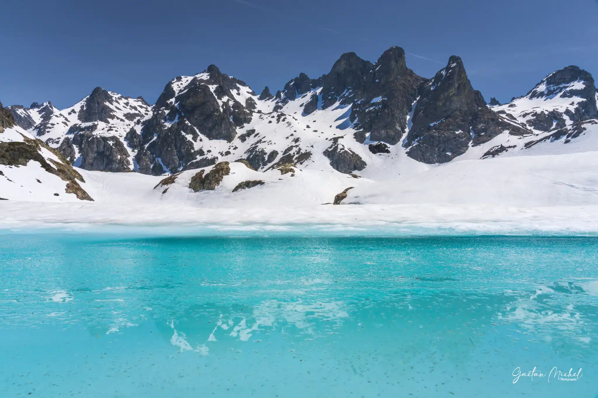 Lacs Robert gelés à Chamrousse dans le massif de Belledonne, avec des eaux turquoise visibles sous la glace Lacs Robert gelés à Chamrousse avec glace et zones d’eau turquoise dans le massif de Belledonne en hiver.