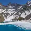 Le Lac Blanc de Belledonne en période de débâcle, avec ses eaux turquoise émergeant de la glace sous les sommets encore enneigés.