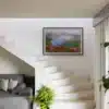 Tableau photo du lac Léama avec rhododendrons roses au premier plan, accroché sur un mur blanc à côté d’un escalier moderne.