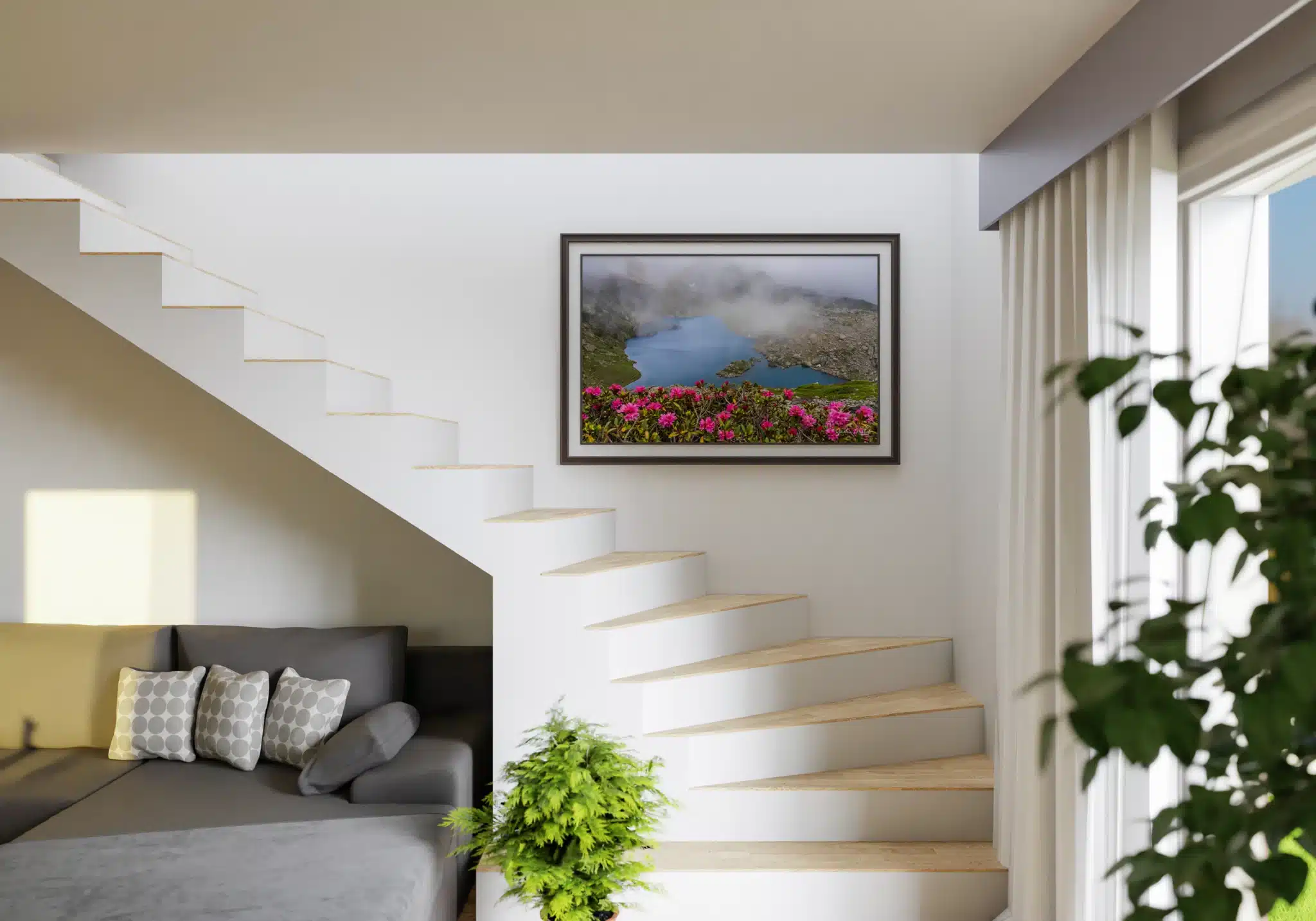 Visualisation du tirage encadré « Lac Léama et rhododendrons » dans un intérieur contemporain. Tableau photo du lac Léama avec rhododendrons roses au premier plan, accroché sur un mur blanc à côté d’un escalier moderne.