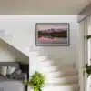 Photographie encadrée des Aiguilles d’Arves au lever du jour accrochée sur un mur blanc à côté d’un escalier moderne.