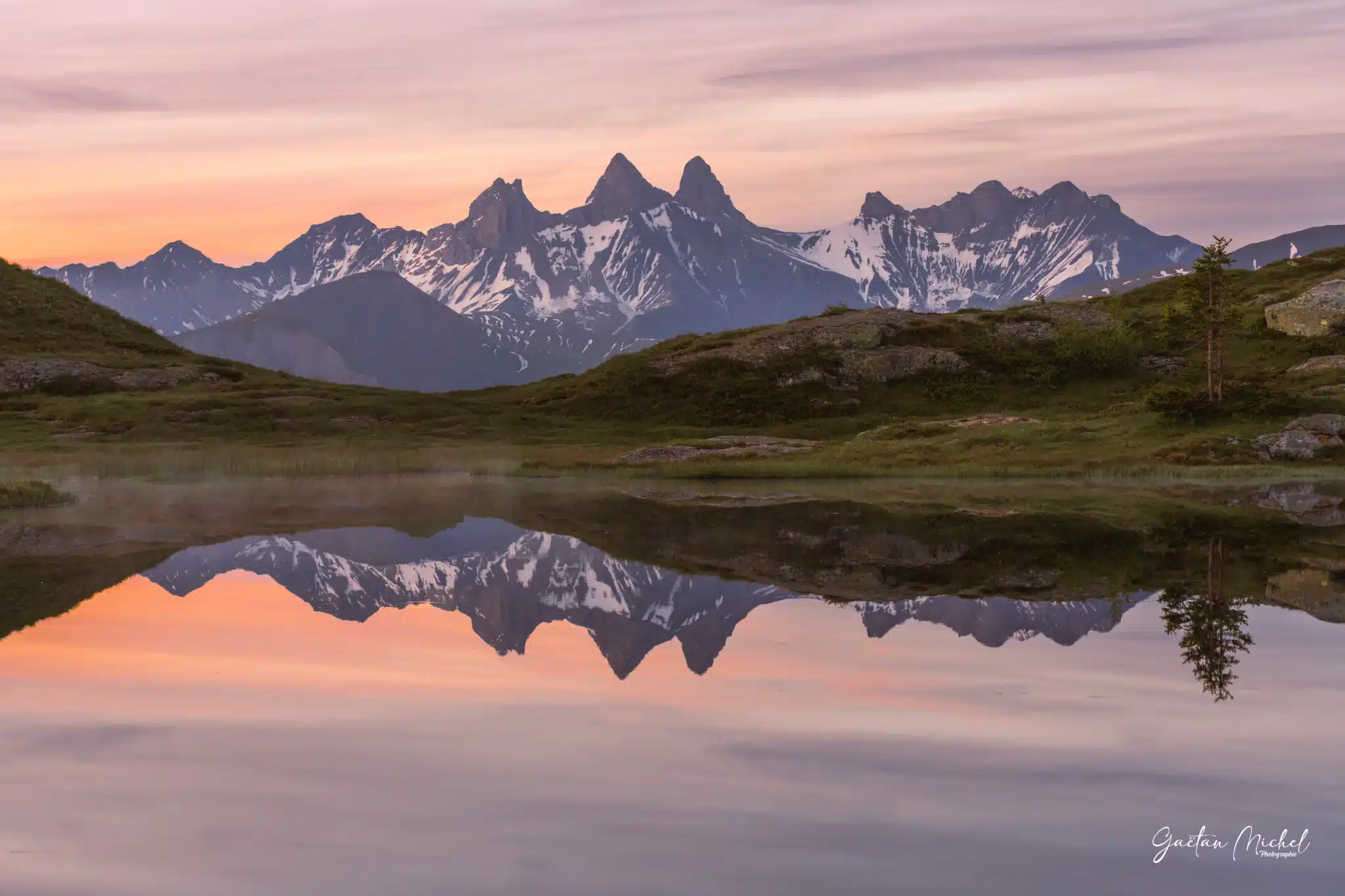 Les premières lueurs de l’aube illuminent les Aiguilles d’Arves, parfaitement reflétées dans le lac Potron. Reflet des Aiguilles d’Arves dans le lac Potron au Col de la Croix de Fer, au lever du jour.