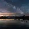 Voie lactée au-dessus des Aiguilles d’Arves se reflétant dans les eaux calmes du lac Guichard lors d’une nuit étoilée.
